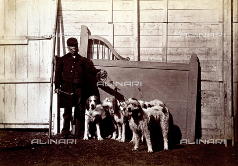 AVQ-A-000477-0003 - Full-length portrait of a man in hunting dress. He is shown holding five dogs on a leash and with a wooden wall in the background - Date of photography: 1865 - Alinari Archives, Florence