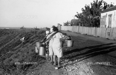AVQ-A-001479-0097 - A group of young Russian peasant women walking along the edge of a road and carrying heavy pails of water on their shoulders - Date of photography: 1942-1943 - Alinari Archives, Florence