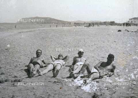 AVQ-A-001479-0132 - Souvenier photo of four young men in bathing suits stretched out on the beach of Cattolica (Italy) - Date of photography: 04/1943 - Alinari Archives, Florence