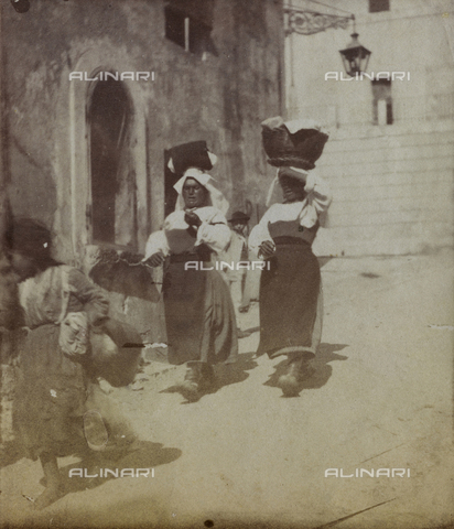 FBQ-F-001203-0000 - Two women in traditional costumes of the area of Lazio are shown along a road in Terracina. They are carrying baskets full of laundry on their heads - Date of photography: 1882 -1887 ca. - Alinari Archives, Florence