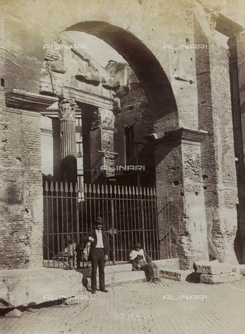 FBQ-F-001207-0000 - Self-portrait, full-length, of Mario De Maria. The photographer is posing at the entrance to an archaeological site closed by a fence. Seated on a step, a man - Date of photography: 1882 - 1887 ca. - Alinari Archives, Florence