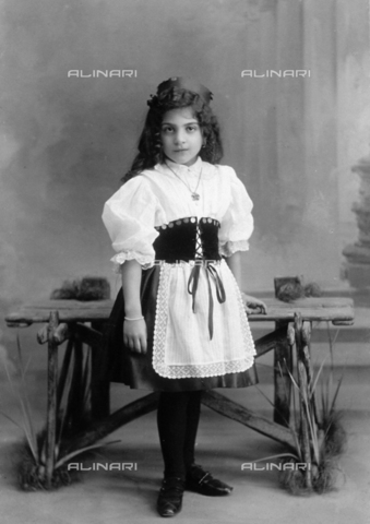 FBQ-F-001432-0000 - Full-length studio portrait of a small girl. She is wearing an italian regional costume with a matching apron trimmed with lace - Date of photography: 1900 - 1910 - Alinari Archives, Florence