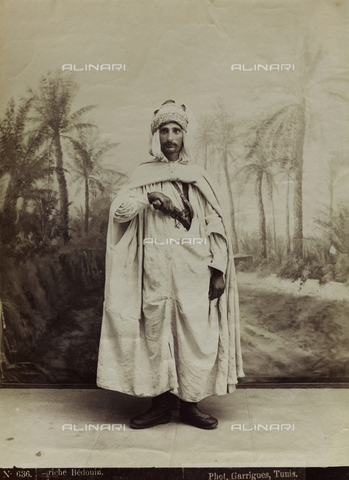 FBQ-F-001503-0000 - Full-length portrait of a rich bedouin in ethnic dress. The young man is shown extracting a pistol from the holster under his tunic - Date of photography: 1860 -1870 - Alinari Archives, Florence