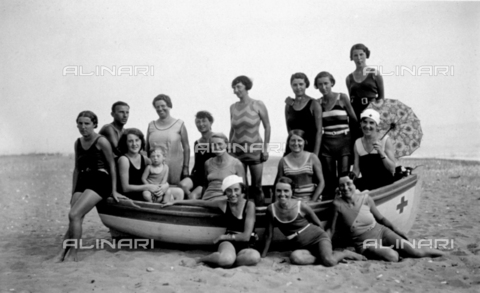 FBQ-F-001926-0000 - Portrait of a group of women in bathing costumes on the beach at Marina di Massa. A few of them are sitting in a boat, the others are standing around it. Among them is a small boy and young man - Date of photography: 1934 ca. - Alinari Archives, Florence