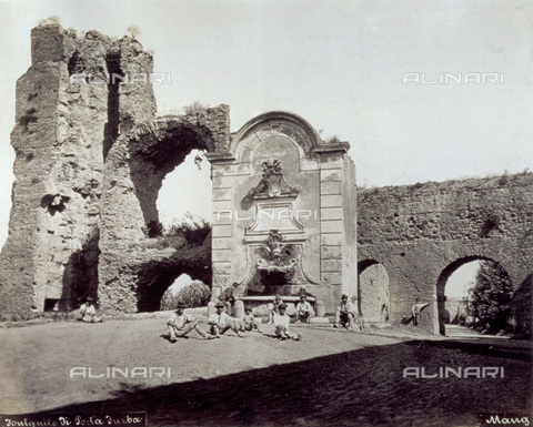 FBQ-F-002594-0000 - The remains of the Porta Furba in Rome and the fountain which stands next to it. In the small piazza in front, a group of men poorly dressed pose for the camera - Date of photography: 1865 - 1885 - Alinari Archives, Florence