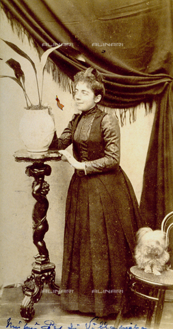 FBQ-F-003993-0000 - Full-length portrait of a noble lady of the Pes di Villamarina family. She is posing next to a wooden column with a plant on top. On her left, seated on a chair, is a little dog - Date of photography: 1880 - Alinari Archives, Florence