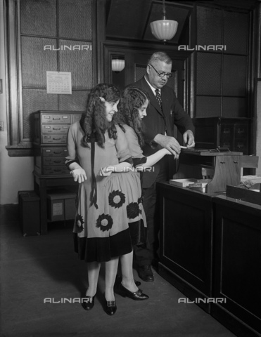 GBB-F-006341-0000 - 1926, 7 october, WASHINGTON, USA: The British-born conjoined twins sisters Daisy and Violet Hilton (1908-1969). In this photo with Fred Sandberg, District police fingerprint expert, tells Daisy and Violet Hilton apart by their fingerprints.The sisters play arole into the celebrated movie FREAKS (1932) by Tod Browning. They were exhibited in Europe as children, and toured the United States sideshow, vaudeville and American burlesque circuits in the 1920s and 1930s. In 1936 Violet married gay actor James Moore as a publicity stunt. The marriage lasted 10 years on paper, but it was eventually annulled. In 1941 Daisy married Harold Estep, better known as dancer Buddy Sawyer, who was also gay. The marriage lasted 10 days. In 1951 they starred in a second film CHAINED FOR LIFE by Harry L. Fraser, an exploitation film loosely based on their lives - © ARCHIVIO GBB / Archivi Alinari