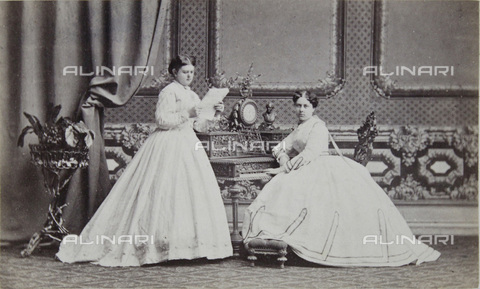 IMA-F-643980-0000 - Two young ladies, the one sitting in front of a desk, the other standing with a sheet of music - Date of photography: 1866 - Victor Angerer / Austrian Archives / brandstaetter images /Alinari Archives