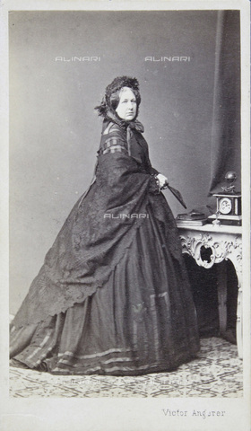 IMA-F-644112-0000 - Lady in a dark dress and with dark hood, on the Atelier table a clock and photo albums, full figure - Date of photography: 1867 - Victor Angerer / Austrian Archives / brandstaetter images /Alinari Archives