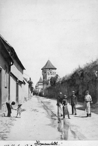 KRQ-F-000013-0000 - A group of people resting on a street in Sibiu (formerly Hermannstadt) in Romania. On the background fortified towers in the city walls are visible. - Date of photography: 1900 ca. - Alinari Archives, Florence