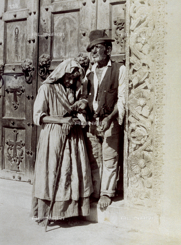 MFC-A-004650-0002 - Beggars on the square in front of a church. One man is stretching out his hand, the woman lowers her head. Both are barefoot - Date of photography: 1890 ca. - Alinari Archives, Florence