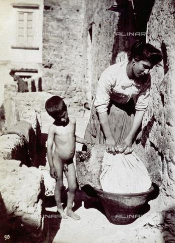 MFC-A-004650-0003 - Young woman washing clothes. She is bending over a tub with a nude child at her side - Date of photography: 1890 ca. - Alinari Archives, Florence