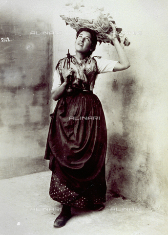 MFC-A-004650-0006 - Portrait of a young woman in folk dress. She has a basket with fruit on her head and a pair of scales on her back - Date of photography: 1890 ca. - Alinari Archives, Florence