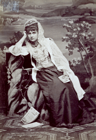 MFC-F-001359-0000 - Full-length portrait of a young woman in traditional dress from Croatia. She is sitting elegantly dressed and is wearing a veil as a headress. A book in hand - Date of photography: 1880-1890 ca. - Alinari Archives, Florence