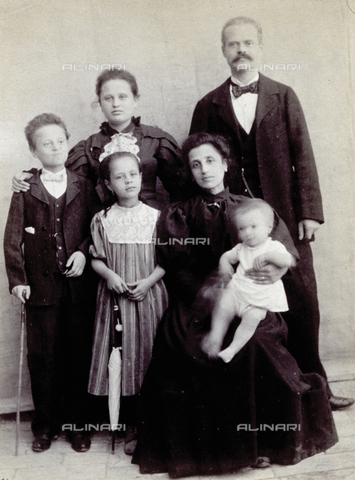 MFC-F-004191-0000 - Full-length portrait of a family group. The mother, seated, holds the small child and is wearing a dark dress with full skirt. The other members of the family are standing behind her - Date of photography: 1880-1890 ca. - Alinari Archives, Florence
