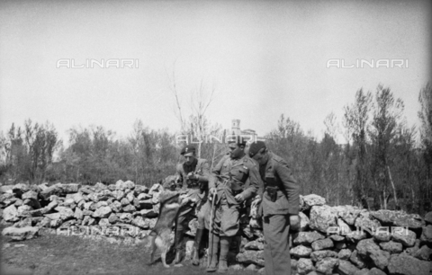 NVQ-S-000321-0054 - Spanish Civil War 1936-1939: Italian fascist soldiers pass through Jerez de la Frontera, Guadalajara, Almadrones, Navalpotro, Calamocha and Labastida to arrive in Santander. Soldiers leaning against a short wall with Spanish town in the background - Date of photography: 1937 - Alinari Archives, Florence