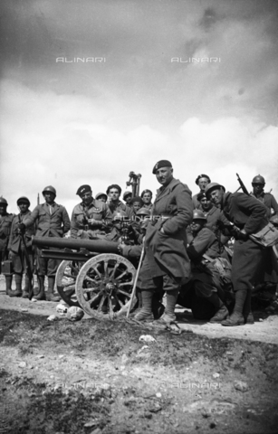 NVQ-S-000321-0101 - Spanish Civil War 1936-1939: Italian fascist soldiers pass through Jerez de la Frontera, Guadalajara, Almadrones, Navalpotro, Calamocha and Labastida to arrive in Santander. Soldiers posing around a cannon with two wheels in Spain - Date of photography: 1937 - Alinari Archives, Florence