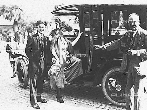 PAS-F-000262-0000 - Due sposi posano per il fotografo prima di salire in automobile. - Data dello scatto: 1920 - Istituto Luce/Gestione Archivi Alinari, Firenze