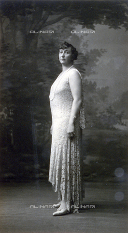 PDC-F-000596-0000 - Full-length portrait of a woman in profile in elegant lace dress embellished/adorned by a long pearl necklace. - Date of photography: 1920-1930 - Alinari Archives, Florence