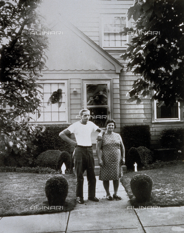 PDC-F-001404-0000 - Experimental photograph of a couple, husband and wife, in front of their home. Behind the entrance door a man can be seen, while a photomontage has put a giant fly on the window - Date of photography: 1973 - Alinari Archives, Florence