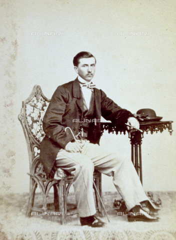PDC-F-001508-0000 - Portrait of a seated young man in day dress with a cigar and a walking stick. On his left, a small table with gloves and hat - Date of photography: 1860 -1870 ca. - Alinari Archives, Florence