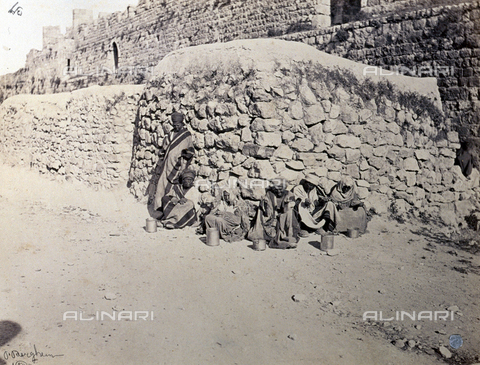 PDC-S-000275-0002 - Group of arab lepers, crouching along the side of a road, along an imposing masonry wall. The figures wear typical garments - Date of photography: 1860-1870 ca. - Alinari Archives, Florence