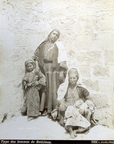 PDC-S-000752-0001 - Full-length portrait of two palestinian women with children, in traditional clothes and jewels. One of them is sitting with a little boy sleeping in her lap - Date of photography: 1880-1900 - Alinari Archives, Florence