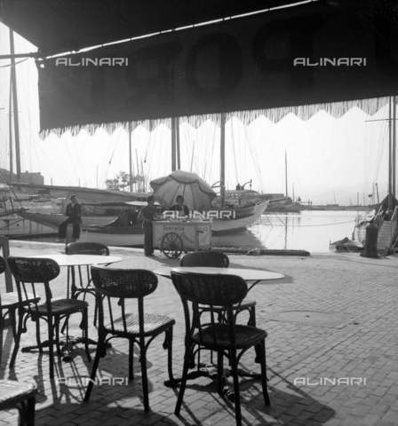 RVA-S-010832-0017 - Terrazza di un caffè e carrettino per vendita gelato sulla banchina del porto di Saint-Tropez - Data dello scatto: 1940-1950 - Laure Albin Guillot / Roger-Viollet/Alinari