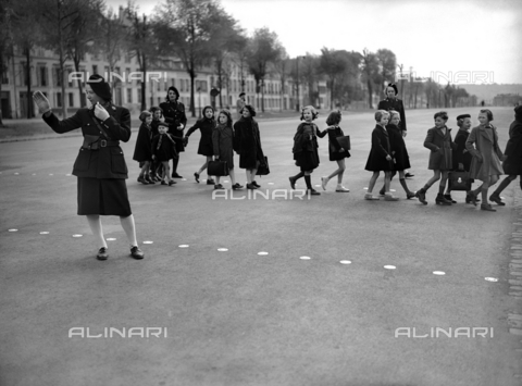 RVA-S-024386-0026 - Ausiliari della polizia aiutano dei bambini ad attraversare la strada sulle strisce pedonali a Versailles - Data dello scatto: 1944 - Lapi / Roger-Viollet/Alinari