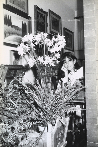 TEA-S-000151-0004 - Luisella Boni posing behind a vase of flowers indoors. - Date of photography: 1968-1978 - Alinari Archives, Florence
